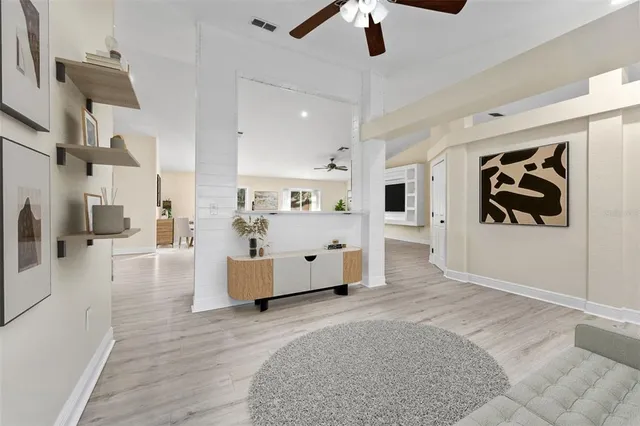 a large white kitchen with stainless steel appliances kitchen island a stove a refrigerator and a fireplace with wooden floor