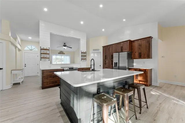 a large kitchen with stainless steel appliances a table chairs and a refrigerator