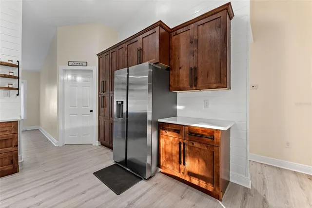 a kitchen with metallic refrigerator and wooden floor