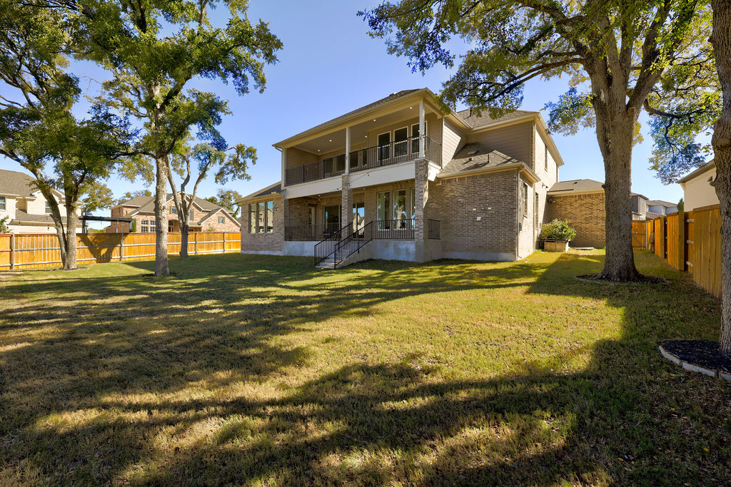 351 Pigeon River Road Kyle, TX 78640 - Photo 23 of 40 Rear view of house featuring a balcony, a fenced backyard, brick siding, and a patio area