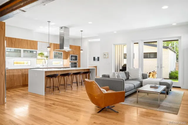 a living room with stainless steel appliances kitchen island granite countertop furniture and a wooden floor