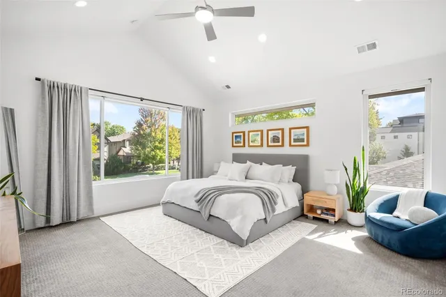 a spacious bedroom with a bed a couch and a large window
