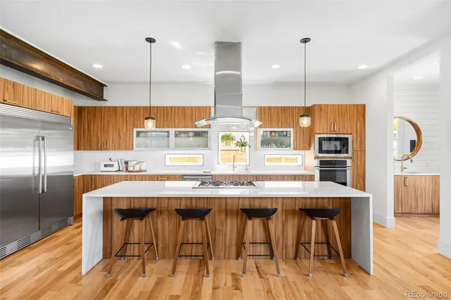 a kitchen with stainless steel appliances granite countertop a kitchen island a stove and a wooden floors