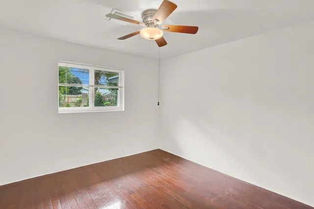 an empty room with a window and a fan