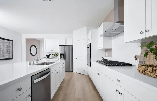a kitchen with stainless steel appliances a sink a stove and white cabinets