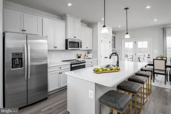 a kitchen with stainless steel appliances granite countertop a refrigerator a stove a sink a dining table and chairs with wooden floor