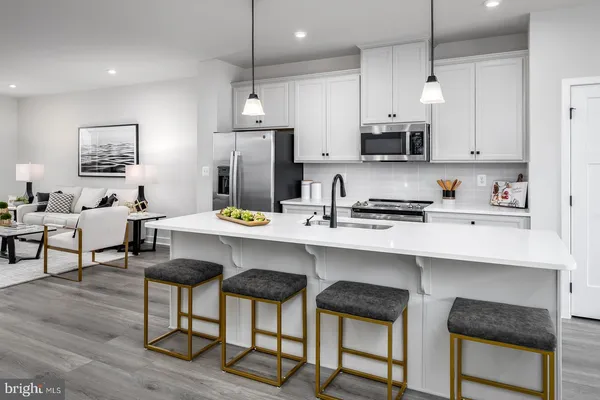 a kitchen with stainless steel appliances a dining table chairs refrigerator and sink
