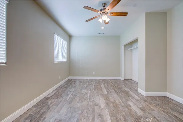 an empty room with wooden floor a ceiling fan and closet