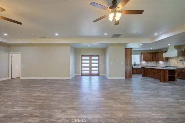 a view of an empty room and kitchen with chandelier fan