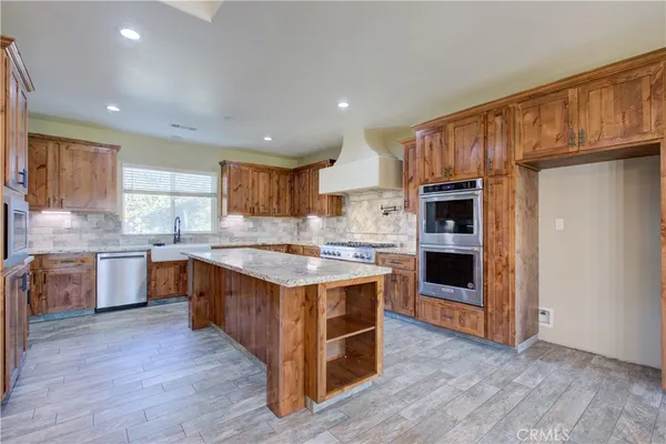 a large kitchen with stainless steel appliances granite countertop a stove a sink dishwasher and a refrigerator