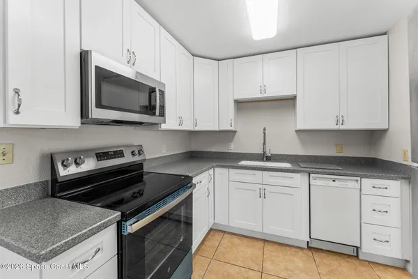 a kitchen with white cabinets and appliances