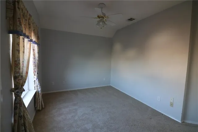 an empty room with a fan & a window