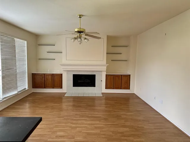 a view of a livingroom with a fireplace a ceiling fan and front door