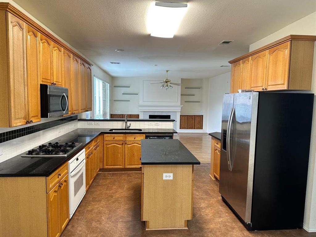 4341 Brinker Court Plano, TX 75024 - Photo 6 of 21 a kitchen with stainless steel appliances granite countertop a refrigerator a stove a sink dishwasher and wooden cabinets with wooden floor