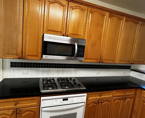 a kitchen with stainless steel appliances granite countertop a stove a sink and a microwave