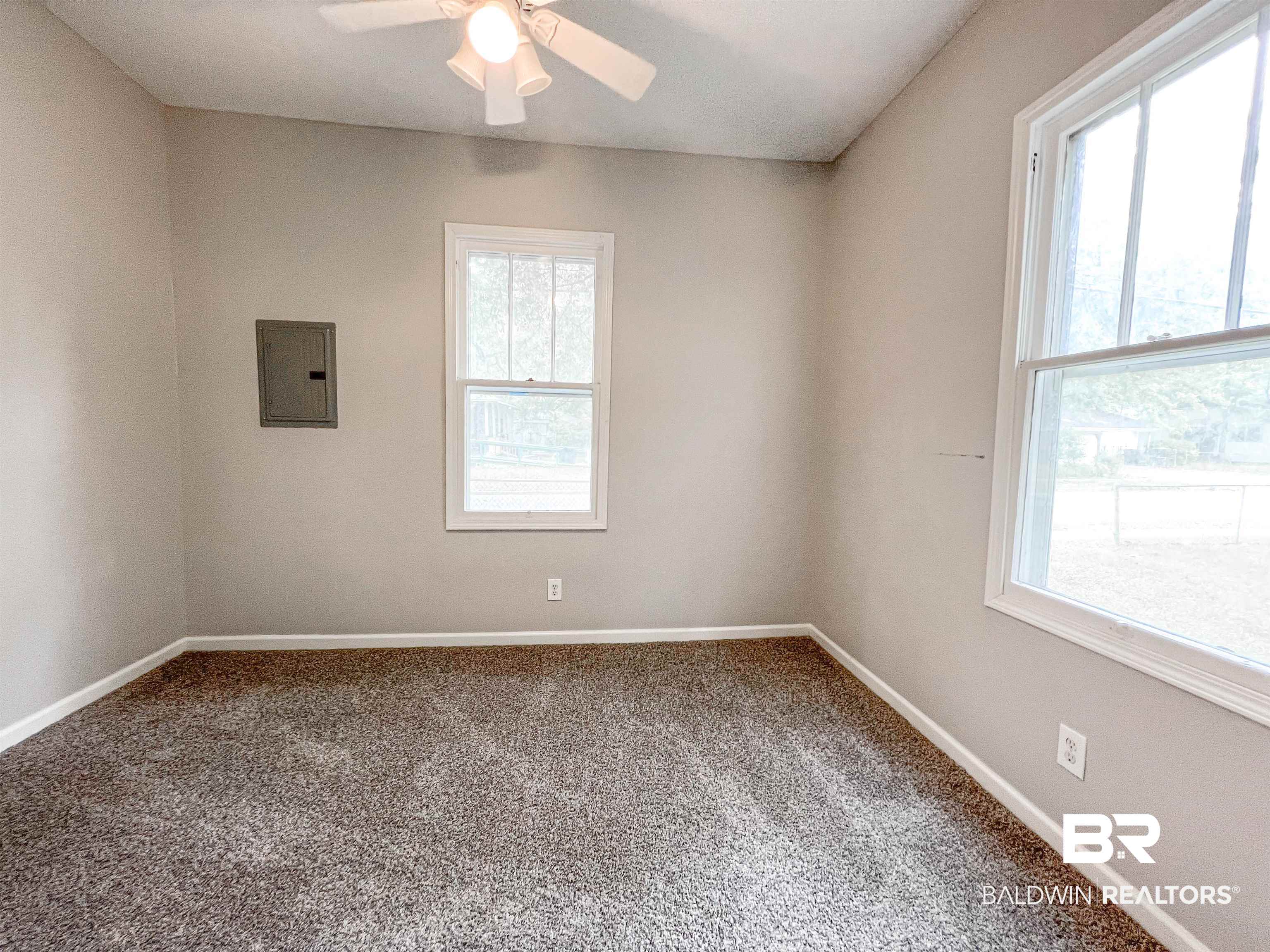 1164 Seneca Street Mobile, AL 36605 - Photo 15 of 22 Carpeted spare room with baseboards, a ceiling fan, electric panel, and a healthy amount of sunlight