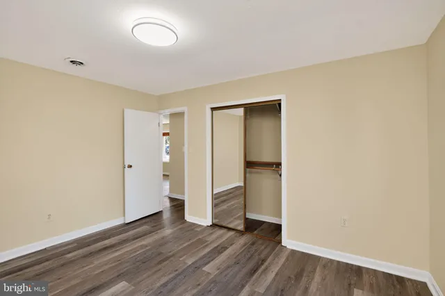 a view of an empty room with wooden floor and closet