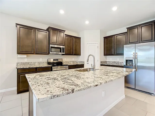 a large kitchen with a large counter top stainless steel appliances and cabinets