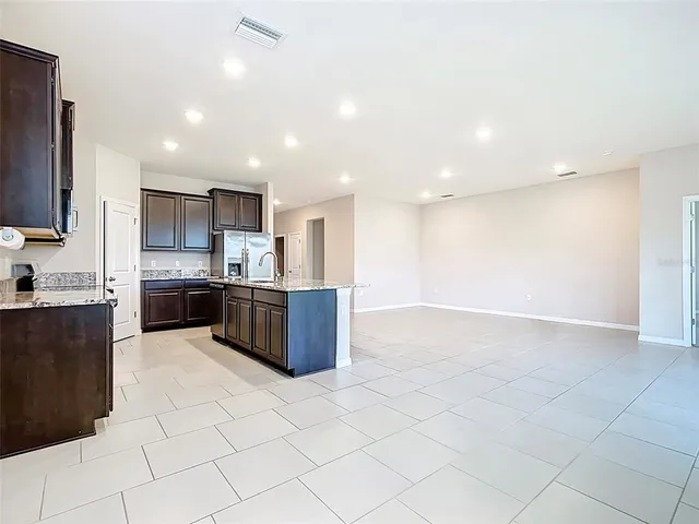 a view of open kitchen with kitchen island granite countertop a stove top oven a sink a counter top space and cabinets