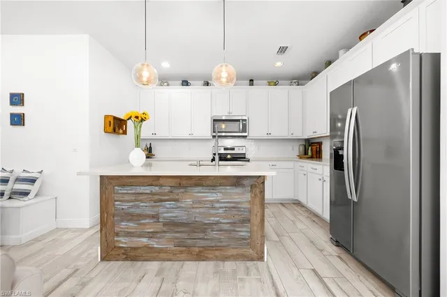 a kitchen with kitchen island white cabinets and stainless steel appliances