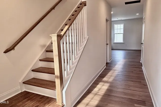 a view of staircase with wooden floor and white walls