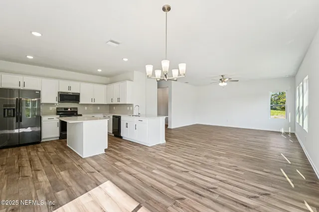 a open kitchen with kitchen island white cabinets and stainless steel appliances