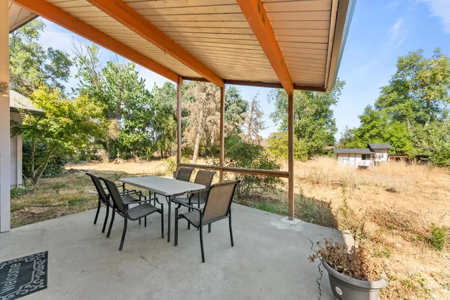 a patio with table and chairs and potted plants