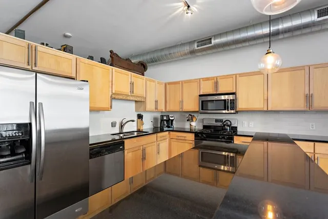 a kitchen with stainless steel appliances granite countertop a refrigerator a sink a stove a microwave and wooden cabinets