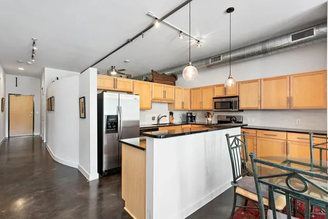 a kitchen with stainless steel appliances a refrigerator a sink dishwasher a stove and white cabinets with wooden floor