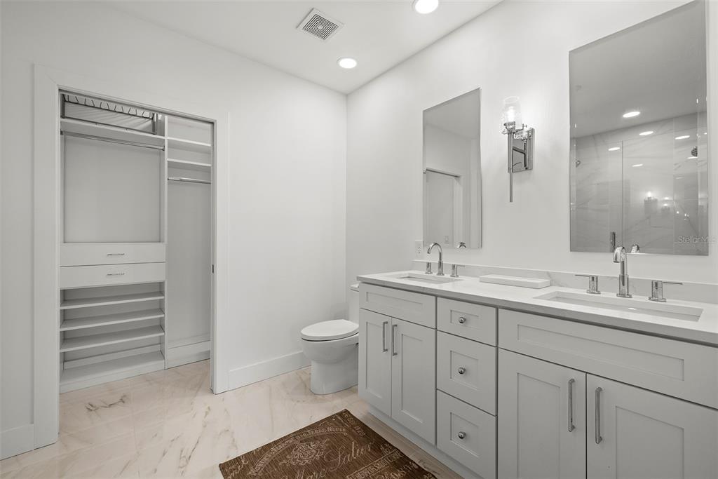 1010 Central Avenue, Unit 302 St. Petersburg, FL 33705 - Photo 22 of 50 a spacious bathroom with a double vanity sink a toilet and a mirror