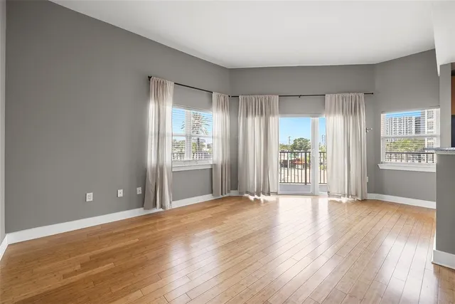 a view of an empty room with window and wooden floor