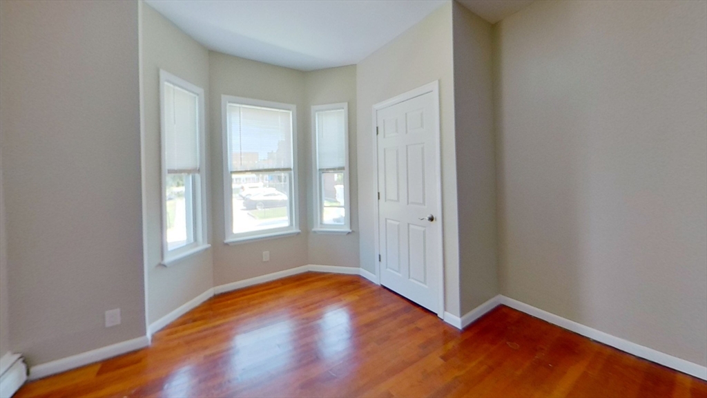 119 George Street, Unit 1 Boston, MA 02119 - Photo 5 of 8 an empty room with wooden floor and windows
