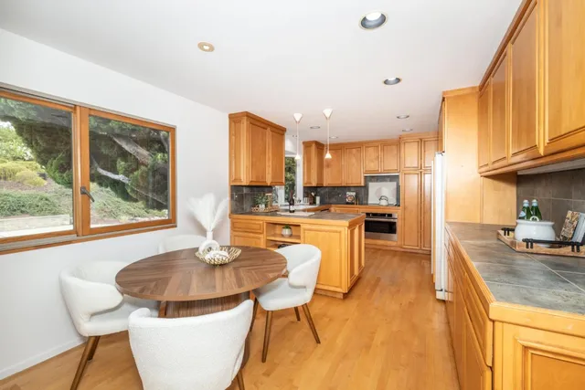 a kitchen with stainless steel appliances granite countertop a stove a sink a microwave a dining table and chairs