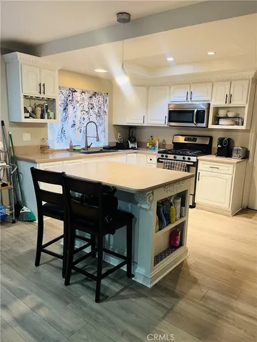 a large kitchen with stainless steel appliances a stove a sink a oven a dining table and chairs