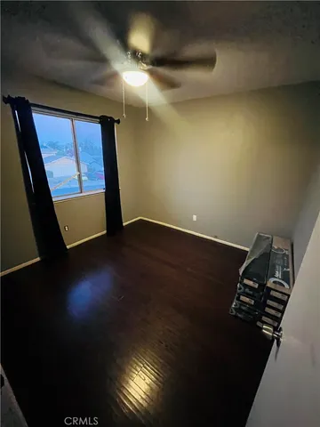 a view of an empty room with wooden floor and windows