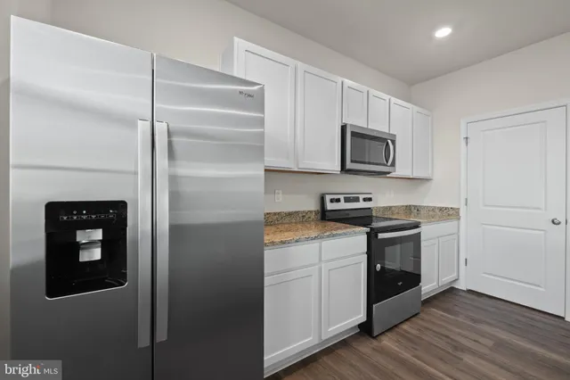 a kitchen with stainless steel appliances granite countertop a refrigerator and a stove top oven