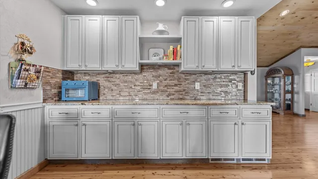 a kitchen with granite countertop a sink cabinets and a wooden floor