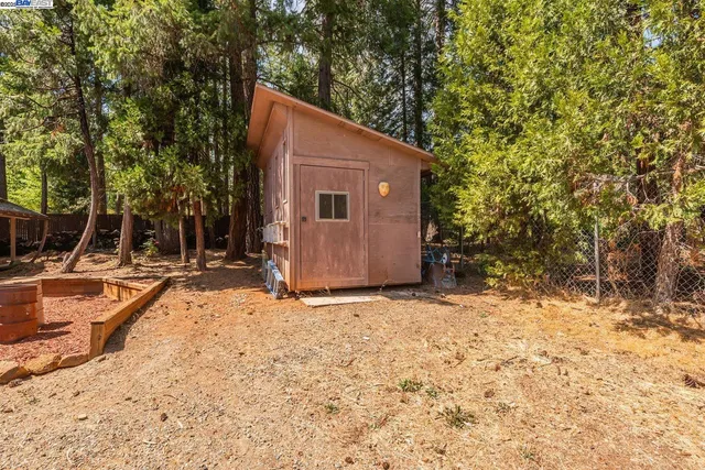 a backyard of a house with large trees and covered with wooden fence