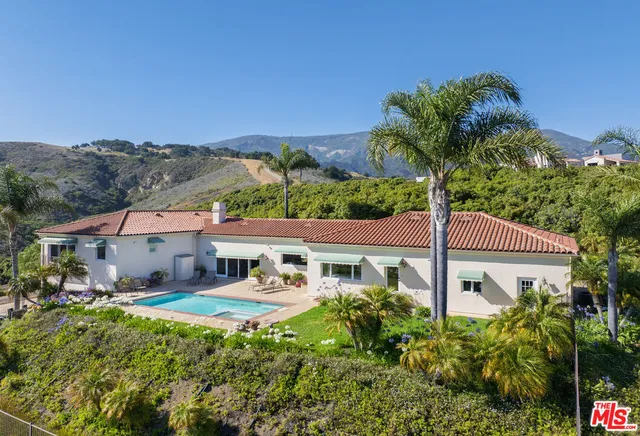 a front view of a house with a yard and potted plants