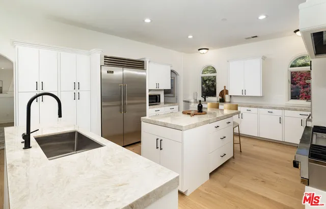 a kitchen with a sink white cabinets and stainless steel appliances