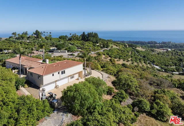 an aerial view of residential house with outdoor space and trees all around