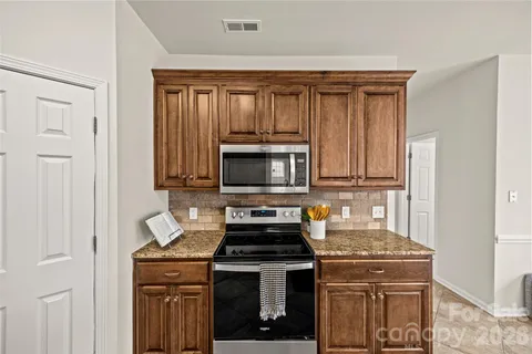 a kitchen with granite countertop a stove sink and cabinets