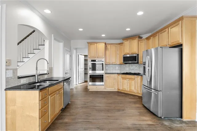 a kitchen with stainless steel appliances granite countertop a refrigerator and a stove top oven