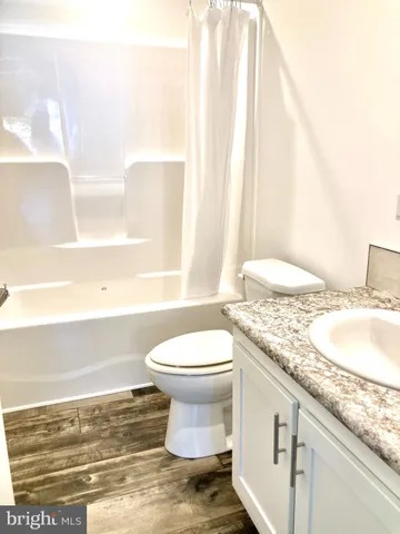 a bathroom with a granite countertop sink toilet and mirror