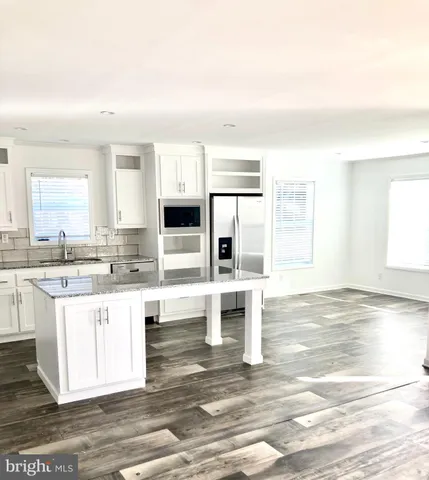 a kitchen with stainless steel appliances granite countertop a stove a sink and white cabinets with wooden floor