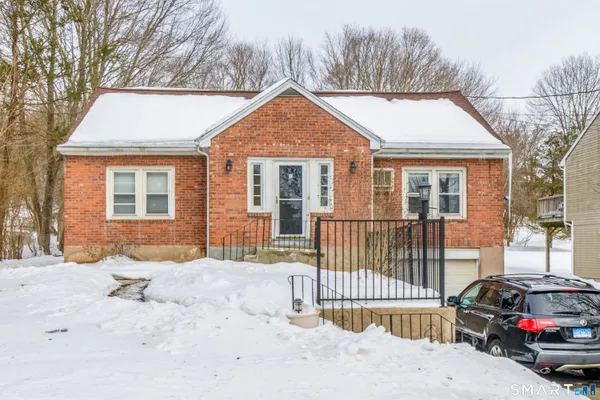 a view of a house with a small yard and large trees