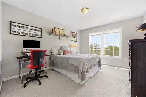 a bedroom with a bed a computer on desk and a dresser next to a window