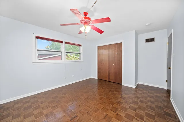 a view of an empty room with window and chandelier fan