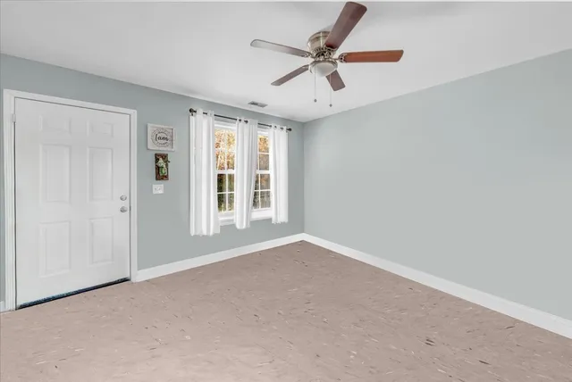 an empty room with a ceiling fan and window