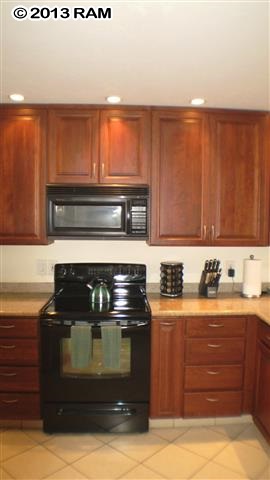 3833 Lower Honoapiilani Road, Unit A203 Lahaina, HI 96761 - Photo 21 of 26 a kitchen with granite countertop a stove and a cabinets